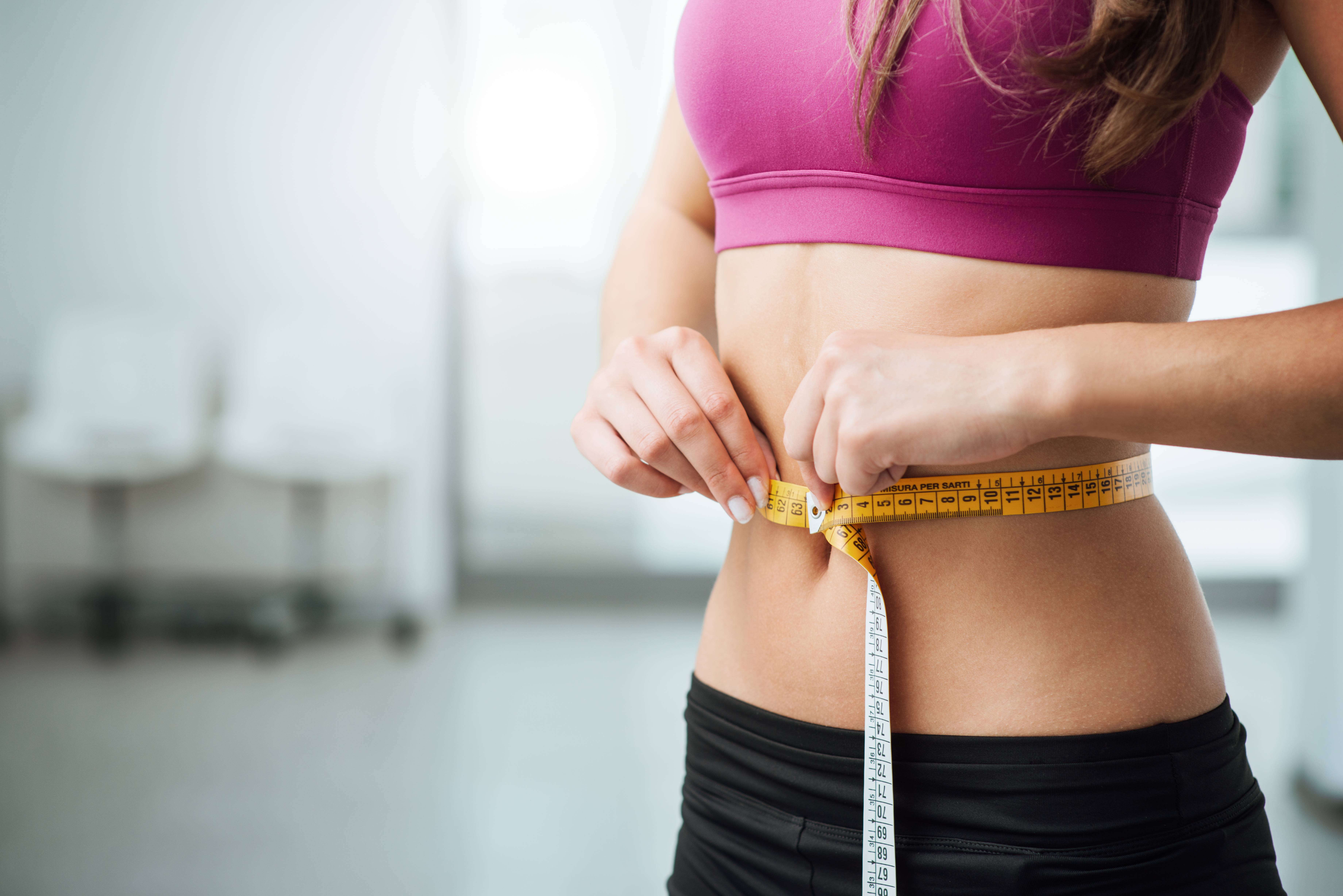 Middrift of an athletic woman measuring her waistline