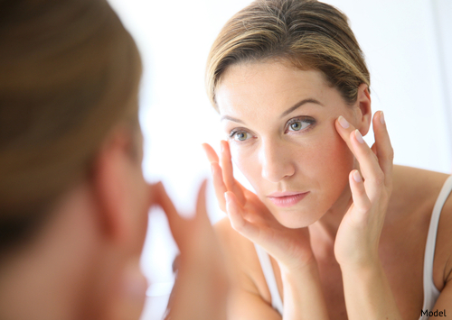 woman looking in mirror considering facelift.