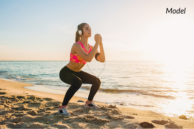 Woman doing squats on beach after tummy tuck surgery.