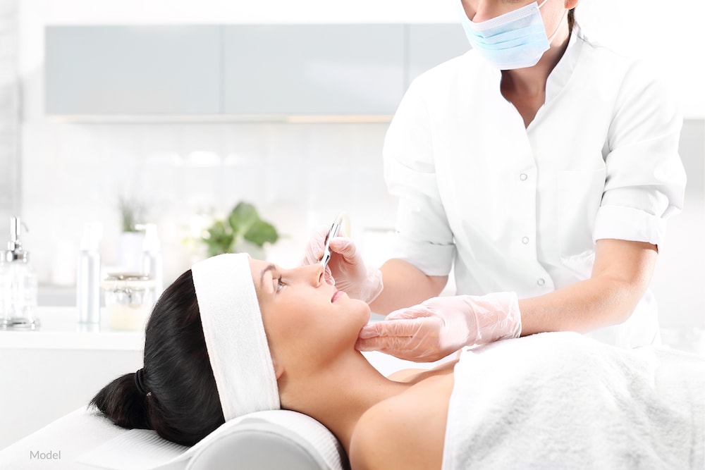 Woman undergoing a microneedling treatment with a plastic surgeon.