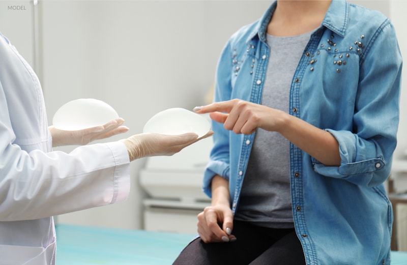 A woman choosing between two different silicone breast implants